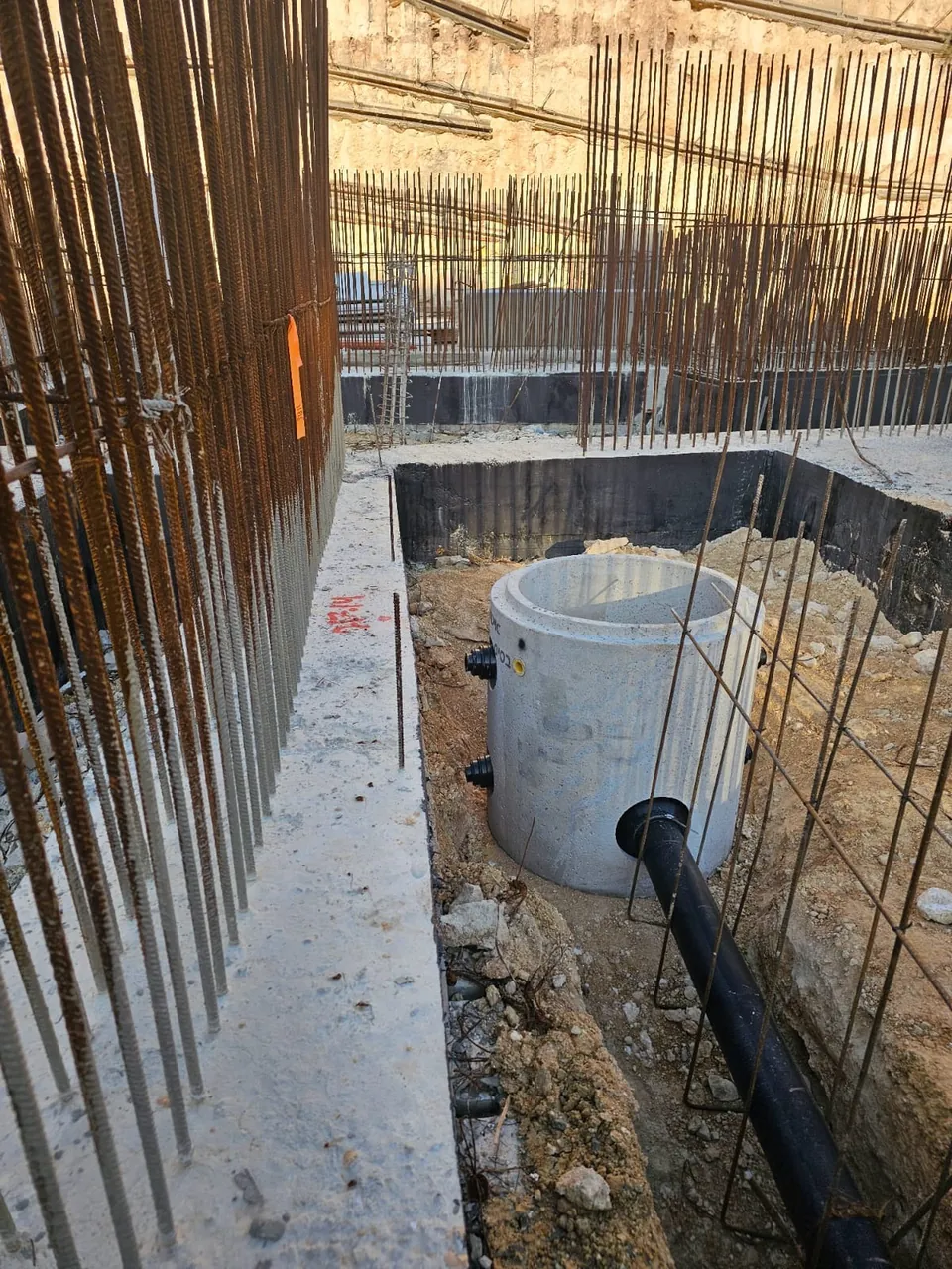 שוחת בטון וקו ביוב ראשי בתוך בור יסודות עם כלונסאות