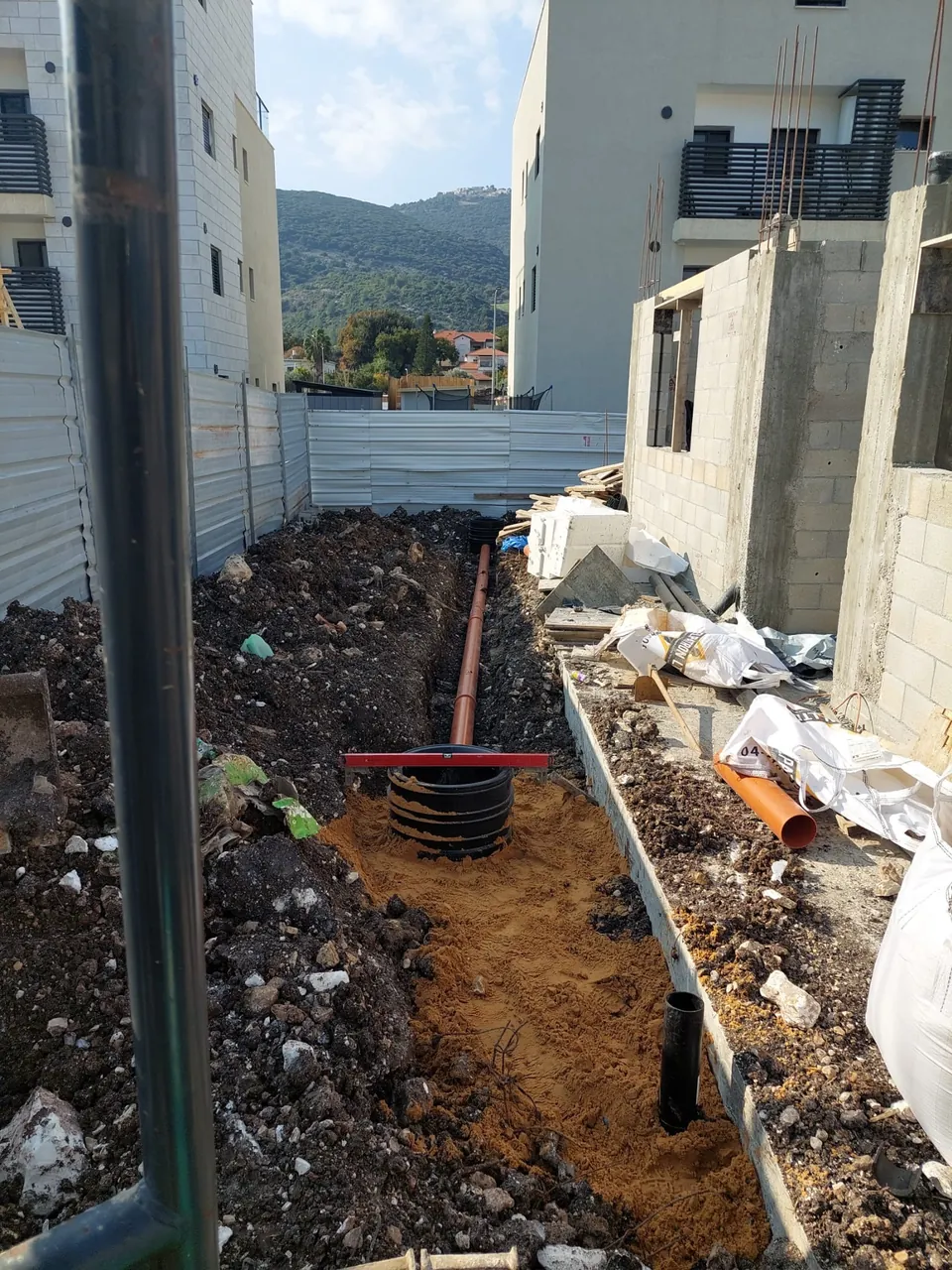 צינור ניקוז גמיש ובסיס שוחה בתעלה פתוחה באתר מגורים