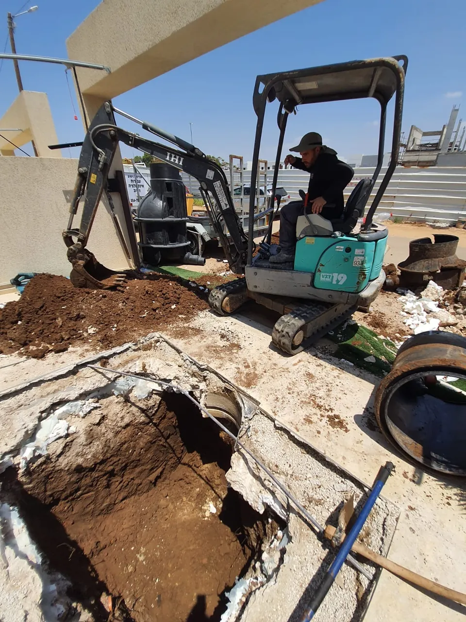 מיני מחפרון פותח משטח מרוצף לצורך גישה לקו תת-קרקעי