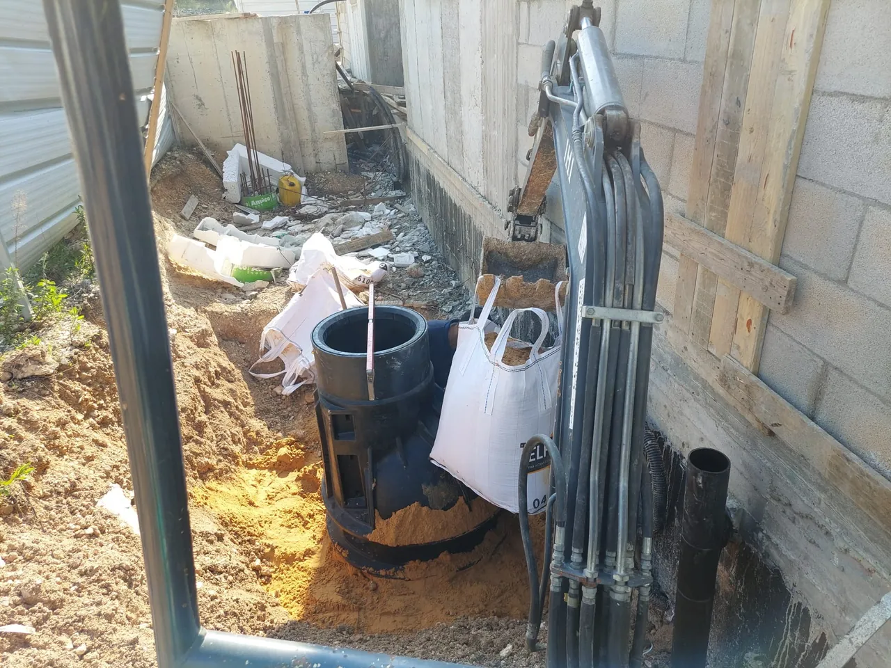 הורדת שוחת פוליאתילן לתוך החפירה בעזרת זרוע המחפרון