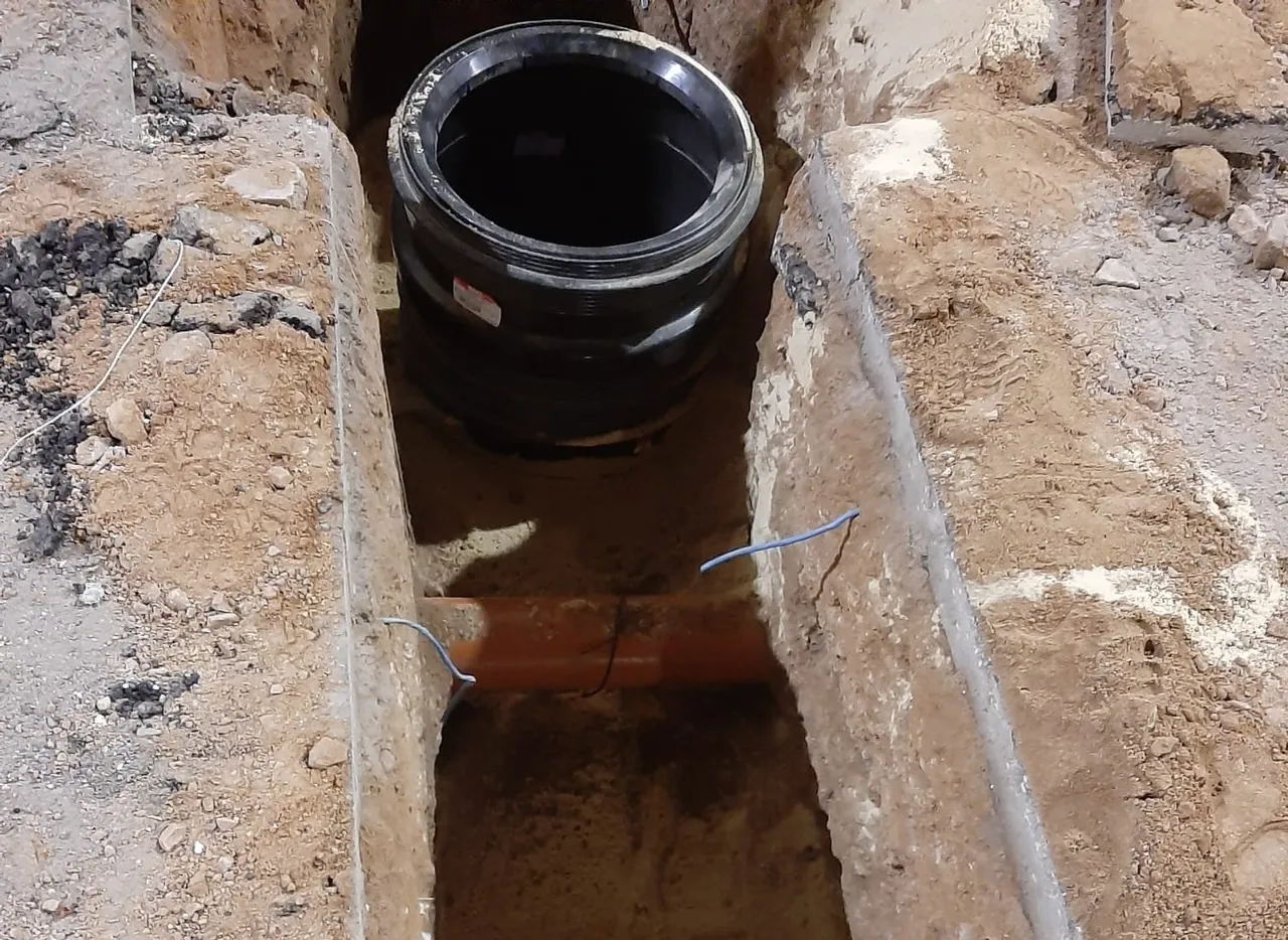 שוחת ביוב שהונחה בתעלה פתוחה לצד קו צנרת באתר תעשייה