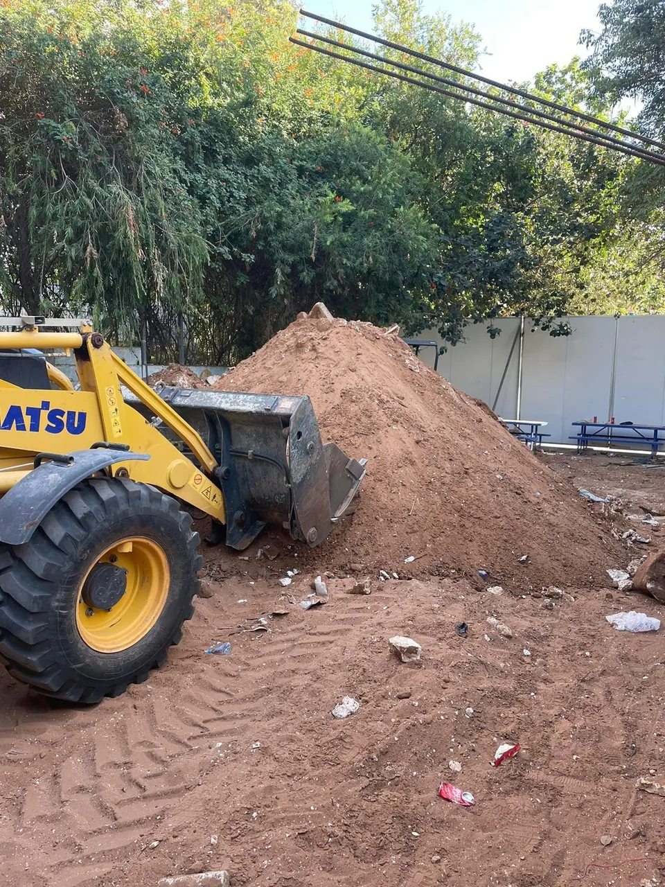 מיני מעמיס מפנה ערימת עפר בחצר אחרי עבודות חפירה