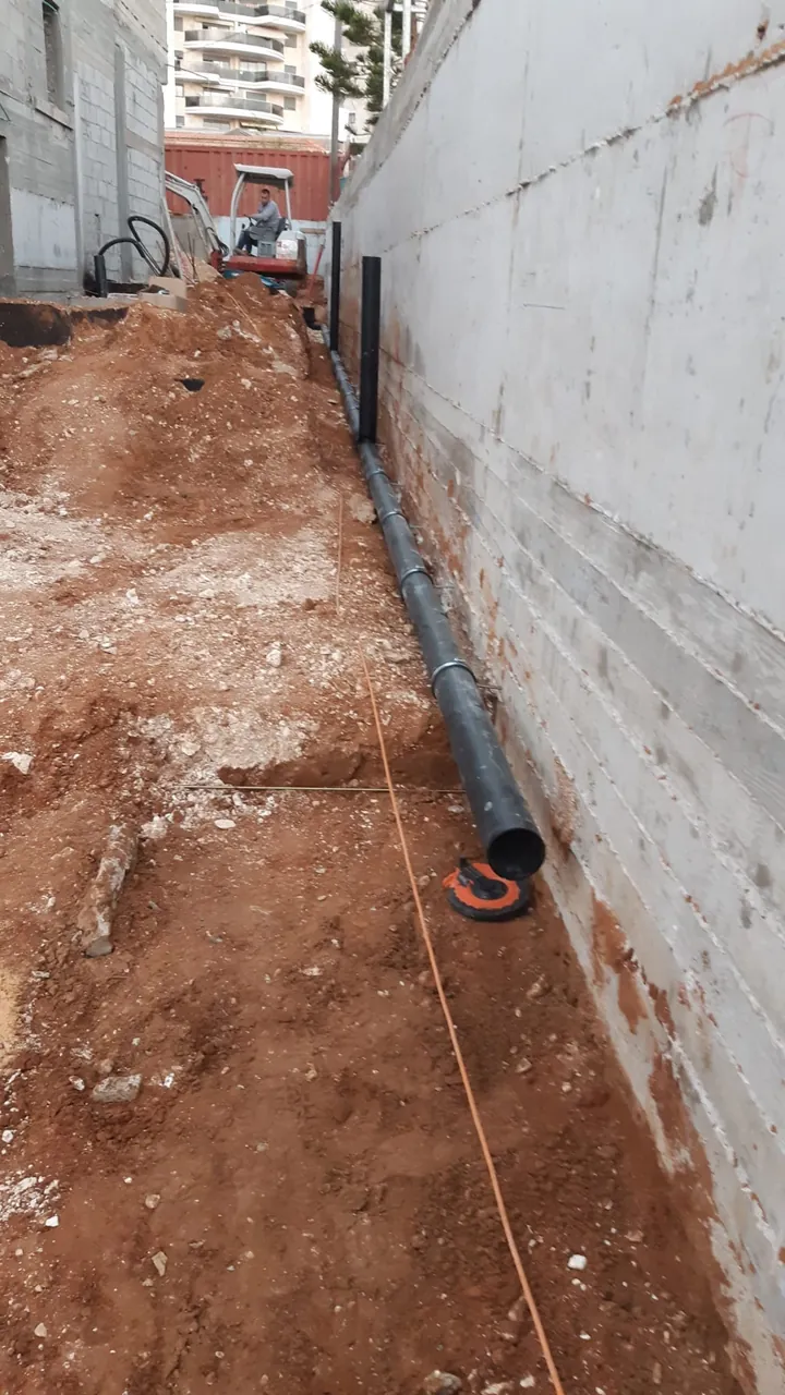 קו ביוב חדש שהונח לאורך קיר מבנה עם חוט מדידה לשיפוע