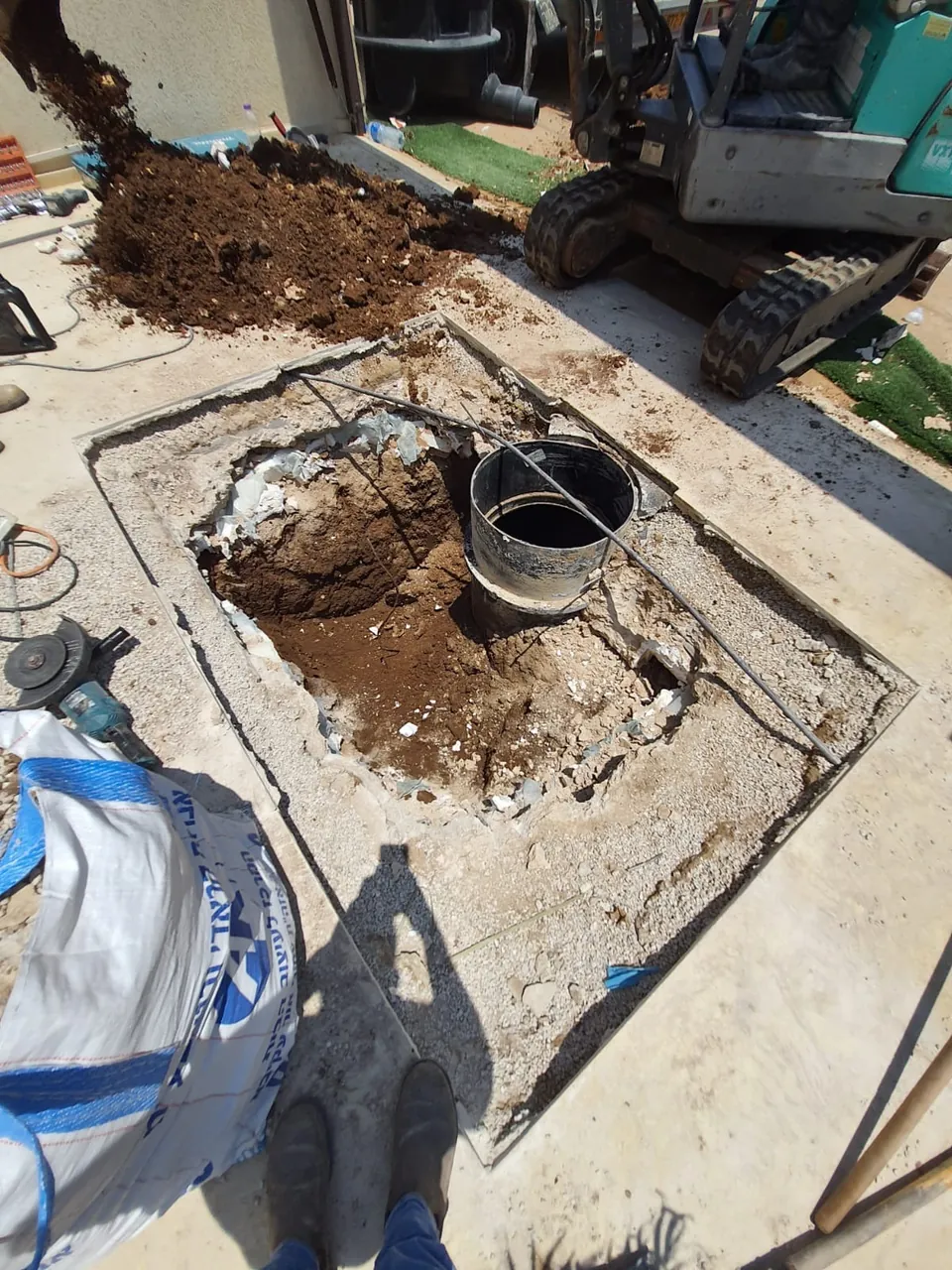 חיתוך מדויק בריצוף לחשיפת שוחת ביוב, עם המחפרון בצד