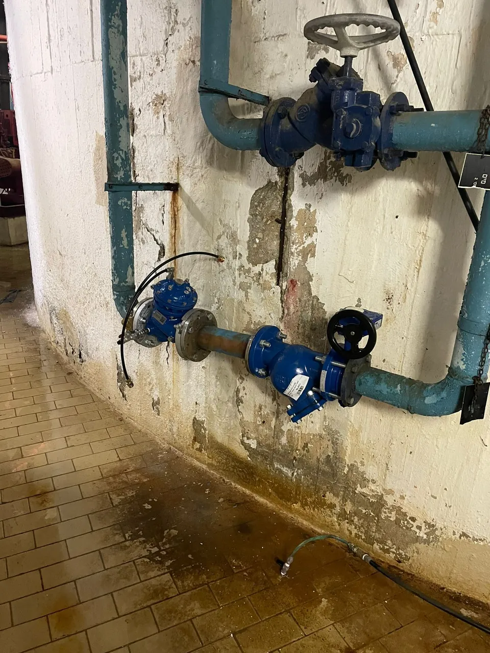 מגופי מים ראשיים על קיר במבנה ציבורי