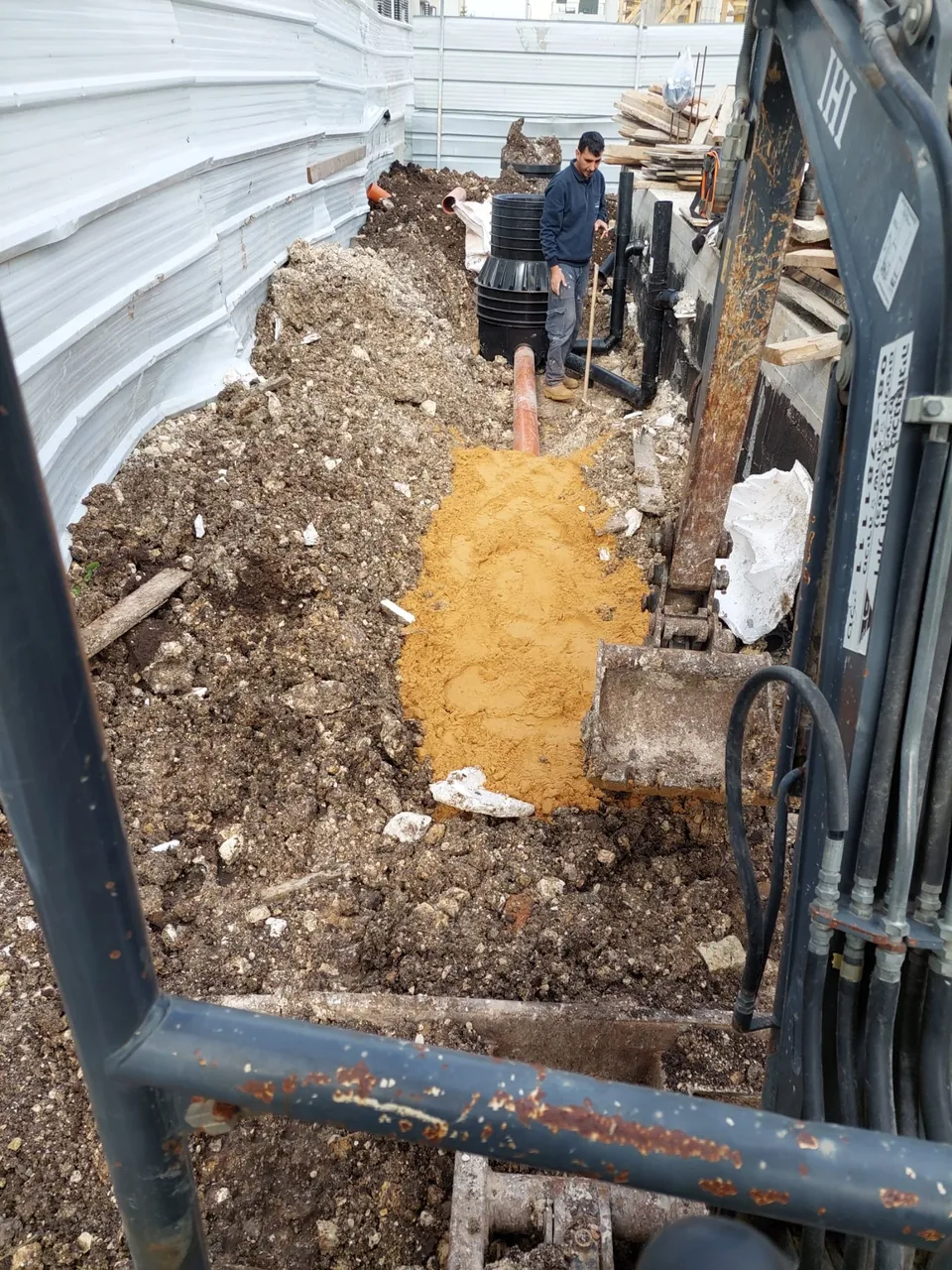 חפירת תעלה לקו ביוב בתוך מבנה מקורה בעזרת מחפרון